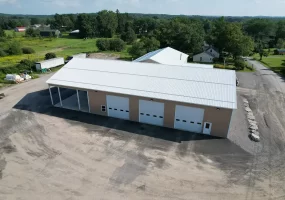 Aerial view of the finished Bennington Highway Department pole barn, highlighting the large open structure, complete with a metal roof, multiple garage doors, and an adjacent storage area.