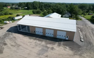 Aerial view of the finished Bennington Highway Department pole barn, highlighting the large open structure, complete with a metal roof, multiple garage doors, and an adjacent storage area.