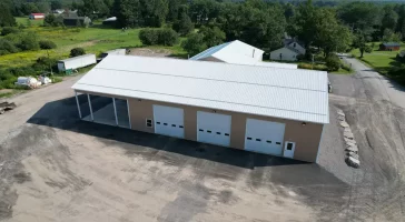 Aerial view of the finished Bennington Highway Department pole barn, highlighting the large open structure, complete with a metal roof, multiple garage doors, and an adjacent storage area.